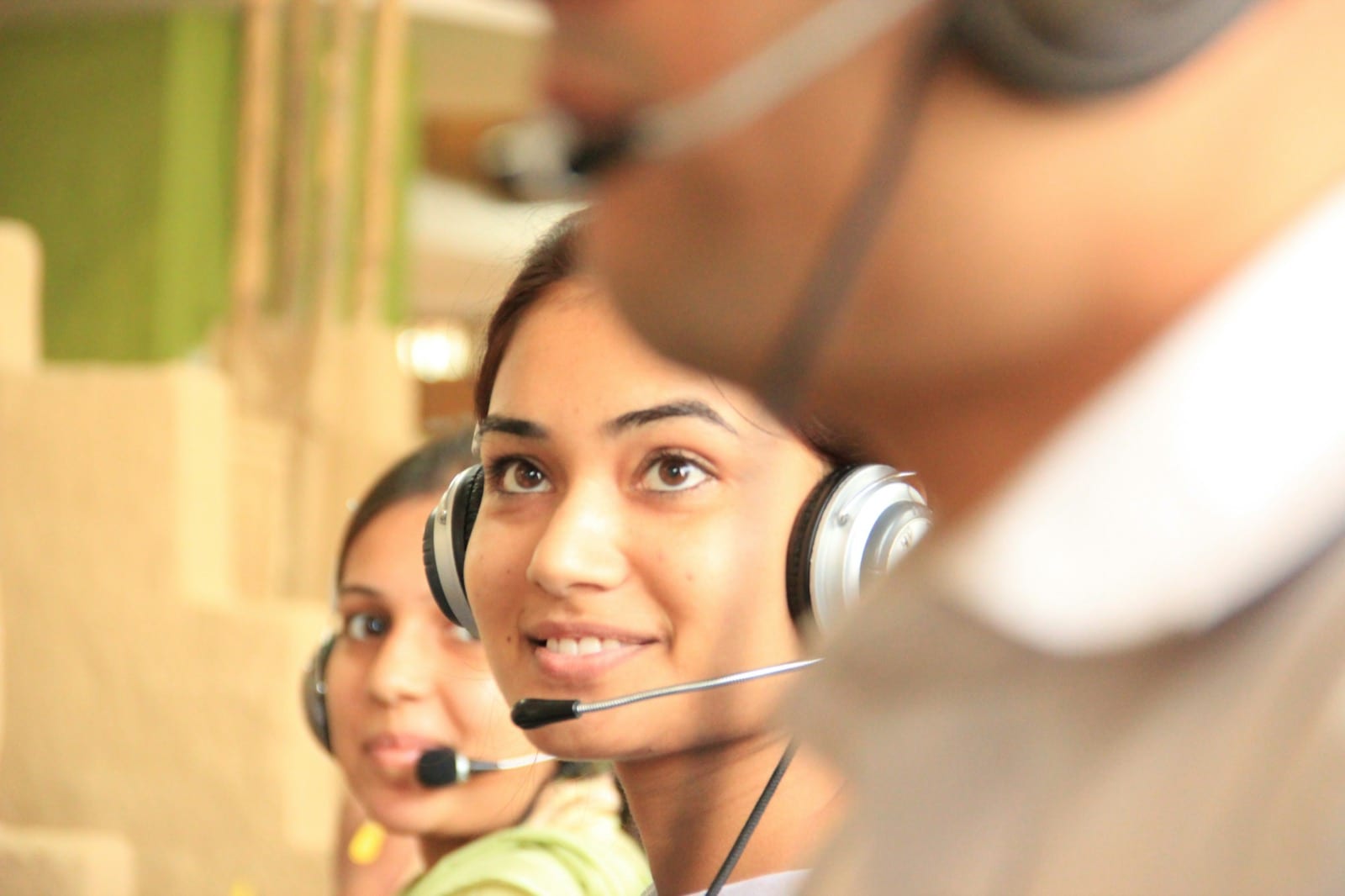 People wearing headsets with microphones work in a call center.