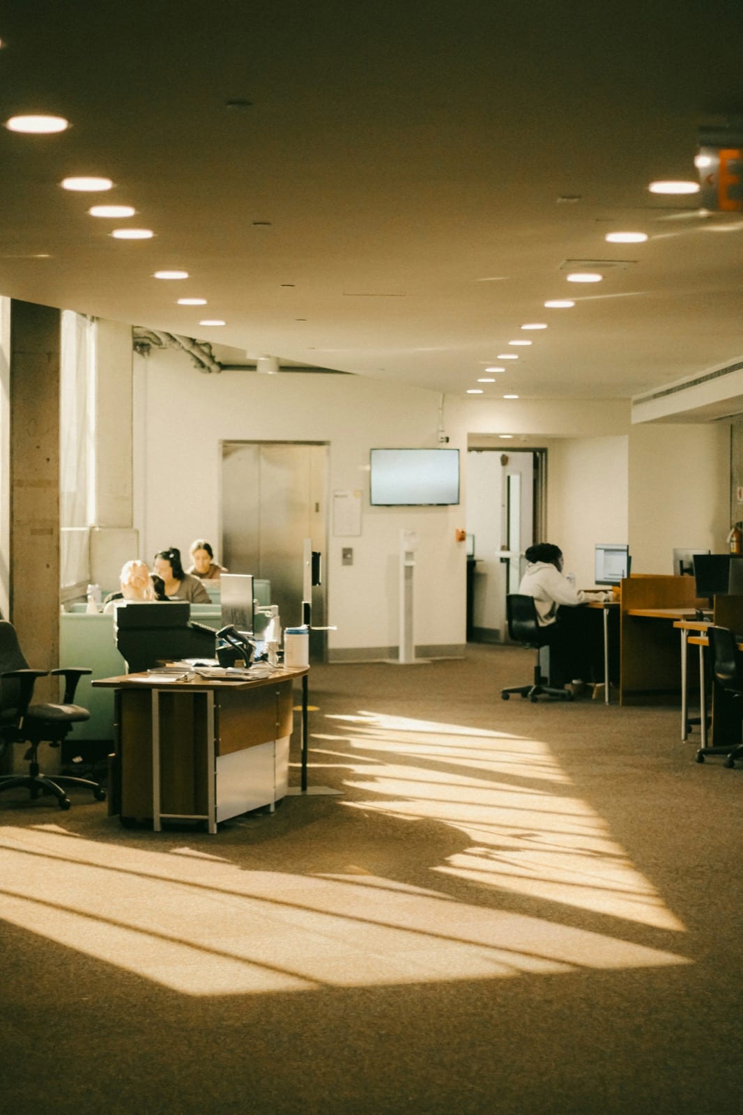 A large open office with service desks and people working at computers.